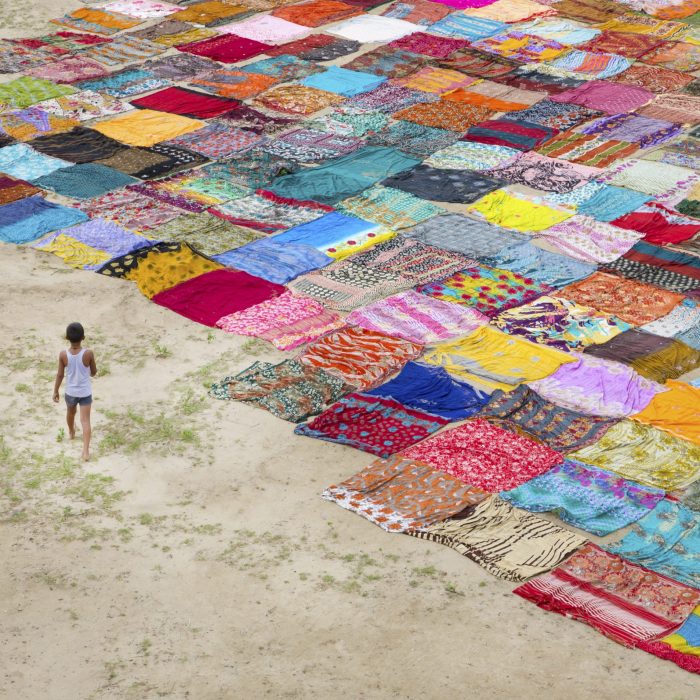 India,Boy by brightly coloured fabric squares laid out on the ground